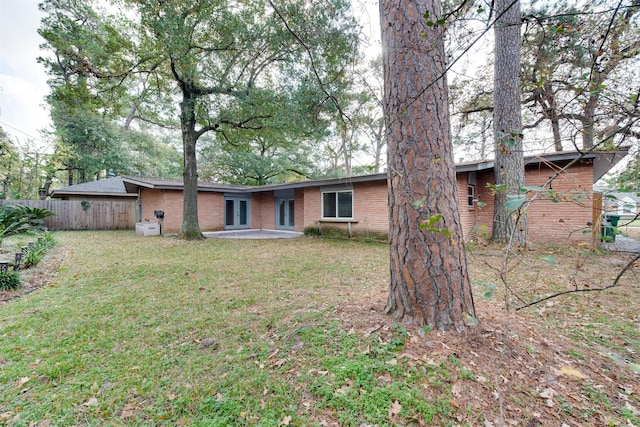 back of house featuring french doors, brick siding, a yard, a patio, and fence