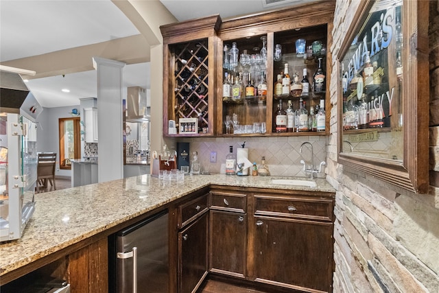 bar featuring wet bar, backsplash, a sink, and exhaust hood