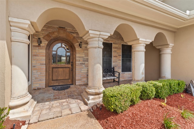 view of exterior entry featuring covered porch and stucco siding