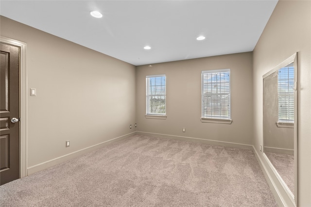 empty room with light carpet, baseboards, and recessed lighting