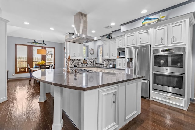 kitchen with island range hood, stainless steel appliances, white cabinets, a large island, and backsplash