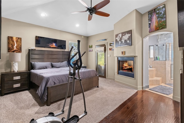 bedroom featuring connected bathroom, recessed lighting, wood finished floors, baseboards, and a glass covered fireplace