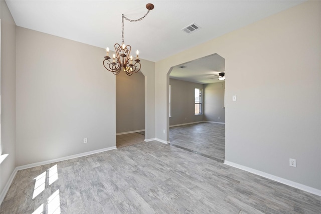 unfurnished room with baseboards, visible vents, arched walkways, wood finished floors, and ceiling fan with notable chandelier