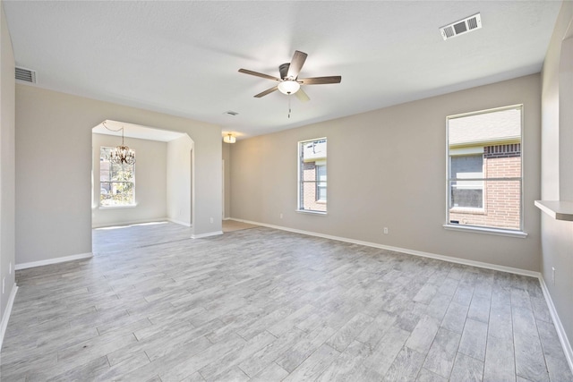 spare room featuring light wood-style floors, visible vents, and ceiling fan with notable chandelier