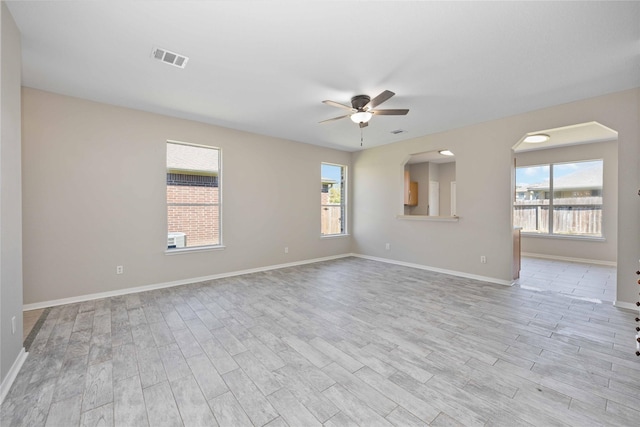 spare room featuring a ceiling fan, plenty of natural light, baseboards, and wood finished floors