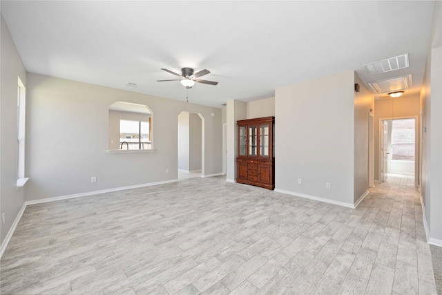 unfurnished room featuring plenty of natural light, attic access, visible vents, and arched walkways