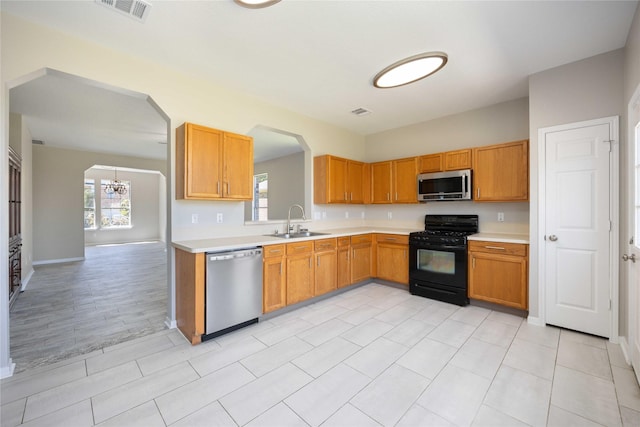 kitchen with arched walkways, light countertops, visible vents, appliances with stainless steel finishes, and a sink