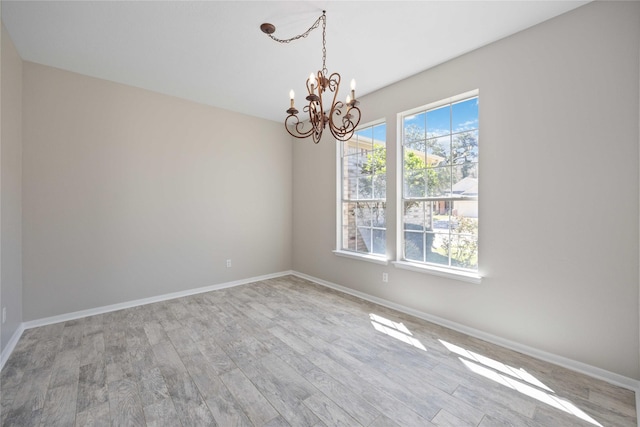 unfurnished room featuring baseboards, a chandelier, and wood finished floors