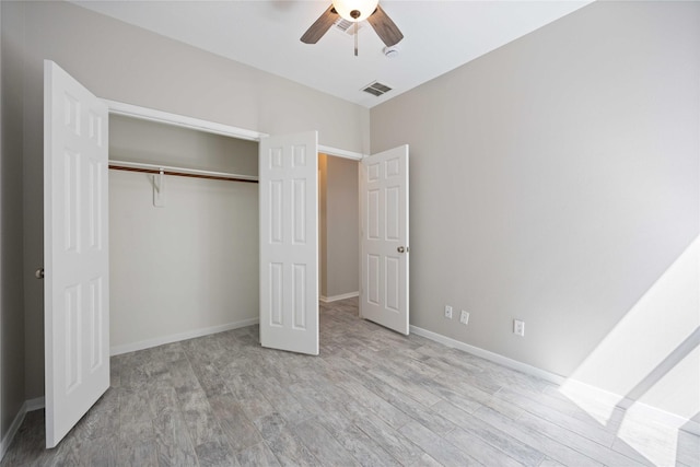 unfurnished bedroom with a closet, visible vents, baseboards, and wood finished floors