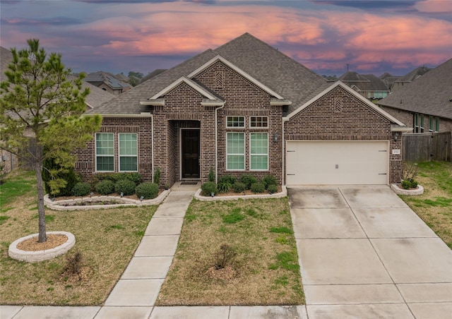 view of front of home with a yard, brick siding, roof with shingles, and an attached garage