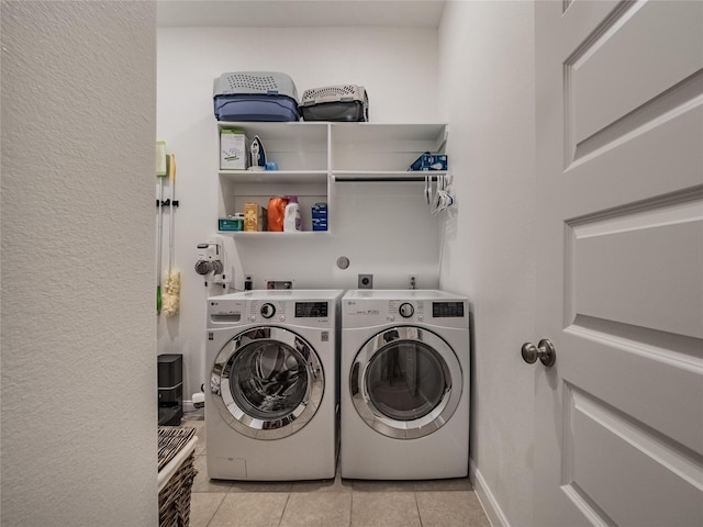 washroom with laundry area, washer and clothes dryer, baseboards, and light tile patterned floors