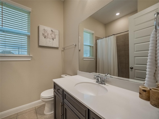 bathroom featuring tile patterned flooring, toilet, vanity, baseboards, and a tile shower