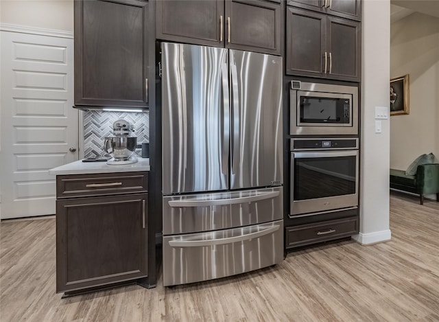 kitchen with light wood finished floors, stainless steel appliances, tasteful backsplash, and dark brown cabinetry