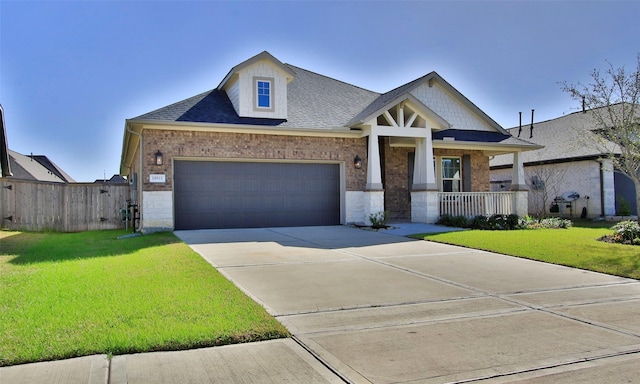 craftsman inspired home with driveway, roof with shingles, a front yard, a porch, and brick siding