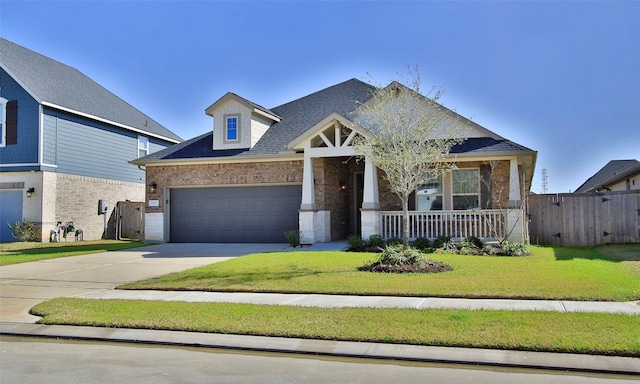 craftsman-style house with concrete driveway, covered porch, fence, a front lawn, and brick siding