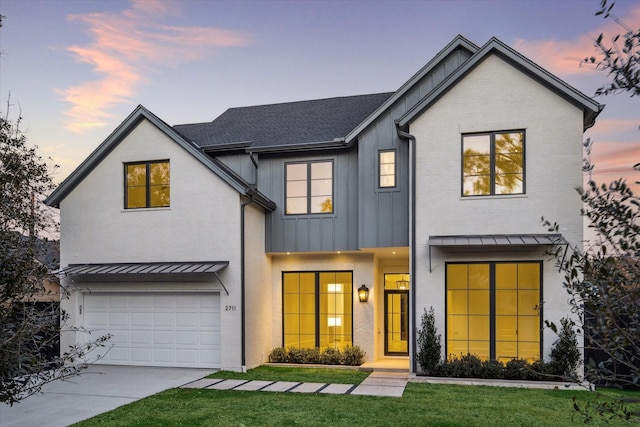 modern inspired farmhouse with an attached garage, concrete driveway, board and batten siding, a standing seam roof, and a front yard