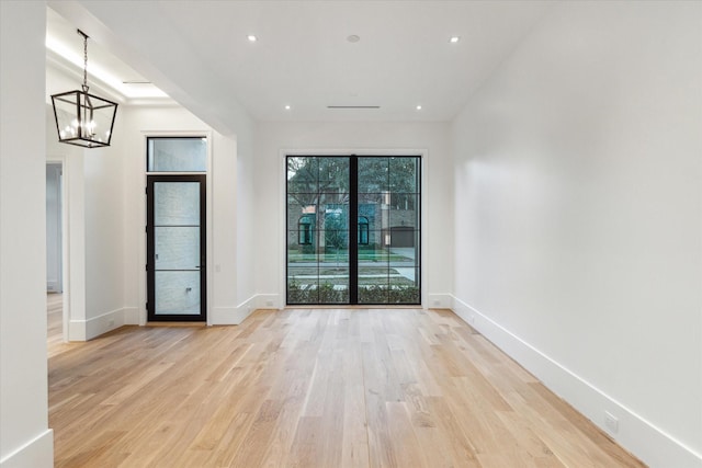 spare room with a chandelier, recessed lighting, light wood-style flooring, and baseboards