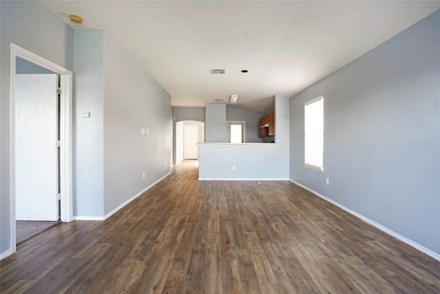 unfurnished room featuring arched walkways, dark wood-type flooring, visible vents, and baseboards