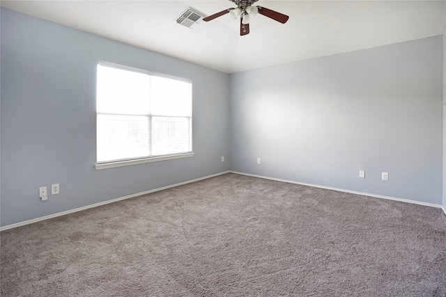 carpeted empty room featuring lofted ceiling, baseboards, visible vents, and a ceiling fan