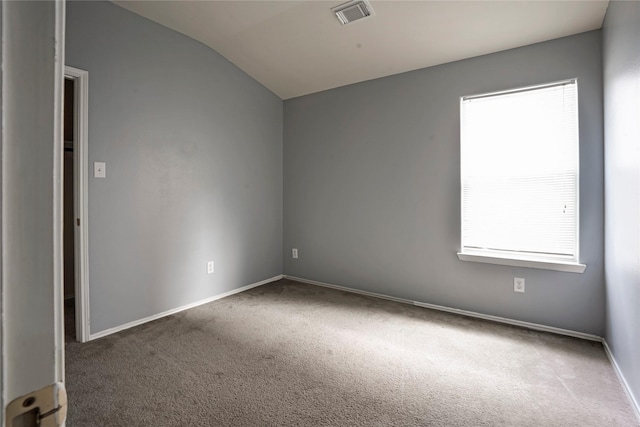 carpeted empty room with baseboards, visible vents, vaulted ceiling, and a wealth of natural light