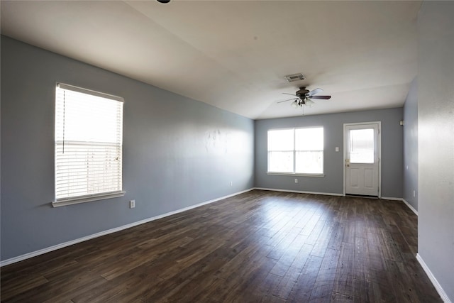 spare room featuring a ceiling fan, visible vents, dark wood finished floors, and baseboards