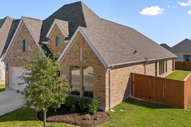 view of side of home featuring a shingled roof, fence, and brick siding