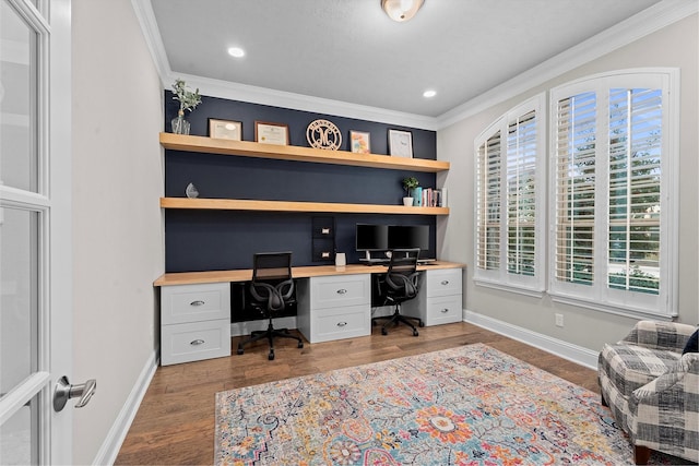 office space with light wood-type flooring, crown molding, baseboards, and built in desk