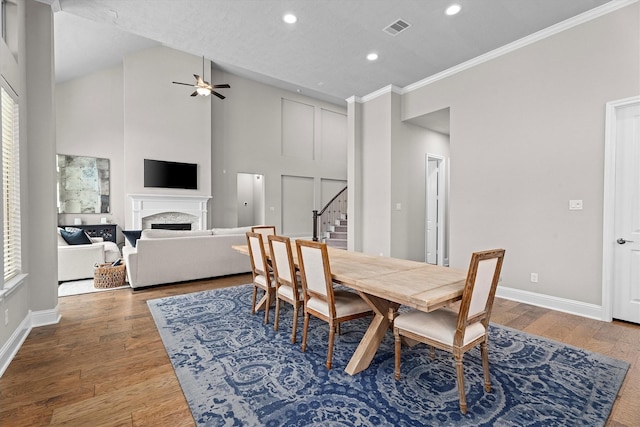 dining room with baseboards, visible vents, stairway, wood finished floors, and a fireplace