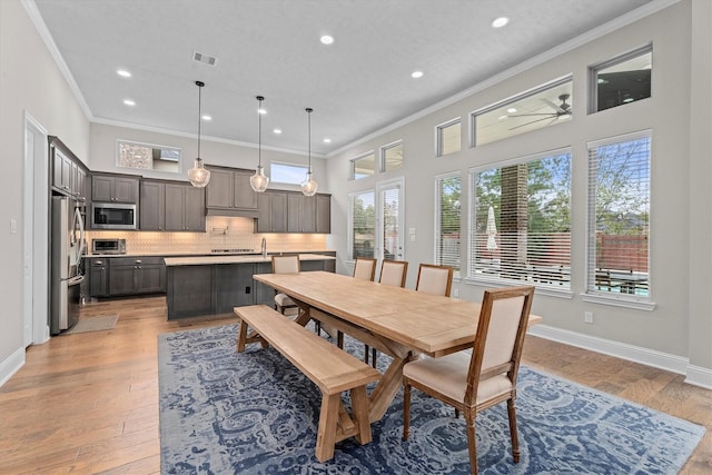 dining space featuring baseboards, ornamental molding, visible vents, and light wood-style floors