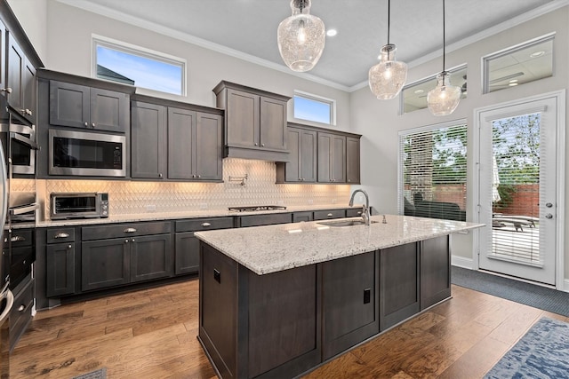 kitchen with appliances with stainless steel finishes, backsplash, a sink, and crown molding