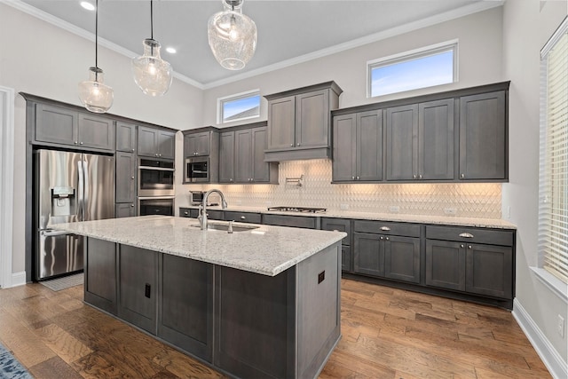 kitchen with light stone counters, appliances with stainless steel finishes, dark wood-type flooring, ornamental molding, and a sink