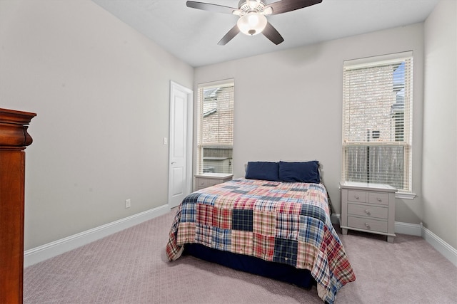 carpeted bedroom with a ceiling fan, multiple windows, and baseboards