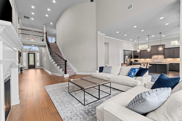 living area with wood-type flooring, visible vents, crown molding, and stairway