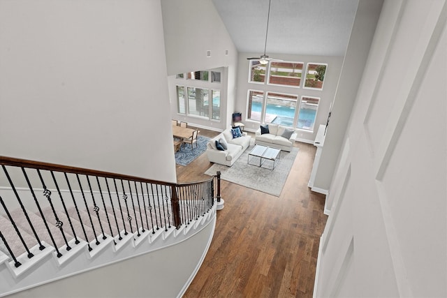 corridor featuring high vaulted ceiling, wood finished floors, and baseboards