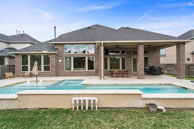 rear view of house featuring a shingled roof, a fenced backyard, ceiling fan, a patio area, and brick siding