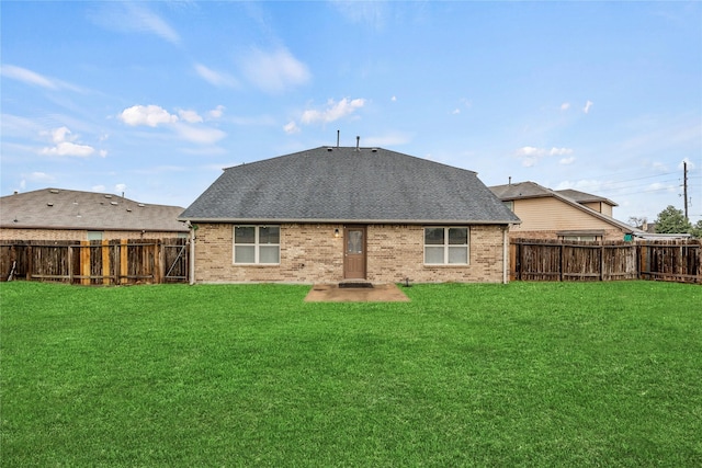 rear view of house featuring brick siding, a shingled roof, and a yard