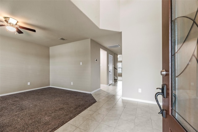 entrance foyer with ceiling fan, light tile patterned flooring, light colored carpet, visible vents, and baseboards