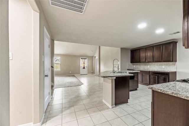 kitchen featuring visible vents, decorative backsplash, open floor plan, dark brown cabinets, and dishwasher