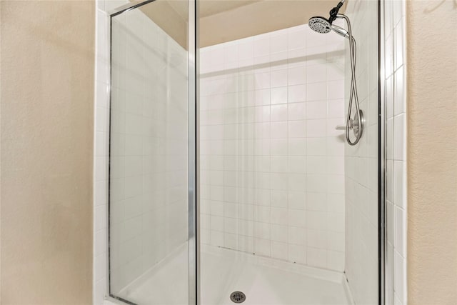 full bath featuring a textured wall and a shower stall