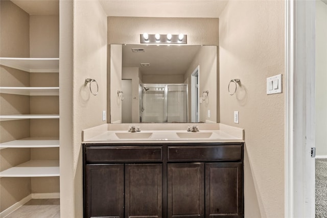 full bathroom with double vanity, tile patterned flooring, a shower stall, and a sink