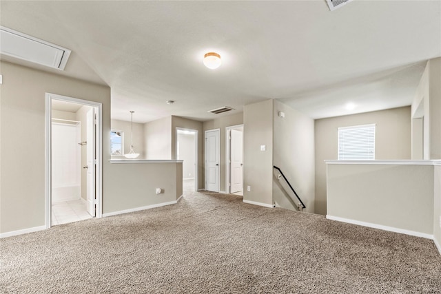 empty room with attic access, carpet flooring, visible vents, and baseboards