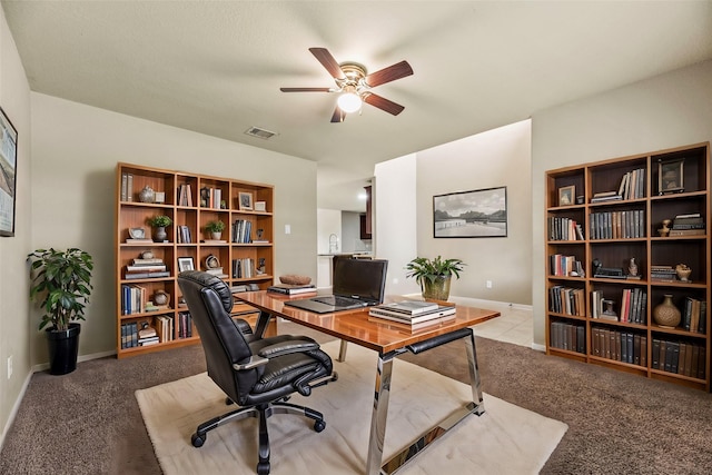 home office with carpet floors, ceiling fan, visible vents, and baseboards