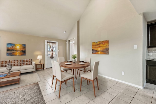 dining area with light tile patterned floors, high vaulted ceiling, and baseboards