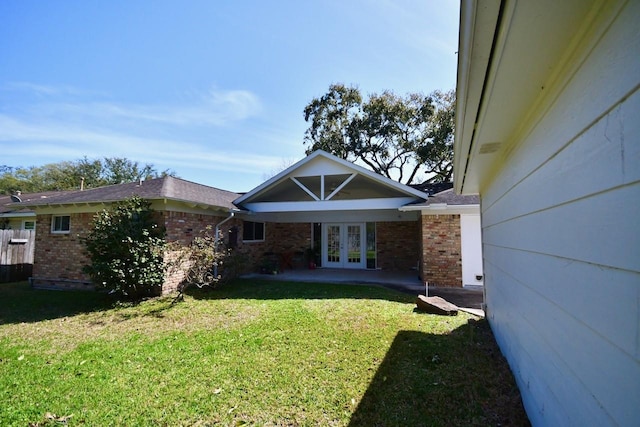 exterior space featuring french doors, brick siding, and a yard