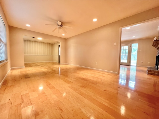 empty room with ceiling fan, recessed lighting, a large fireplace, baseboards, and light wood finished floors