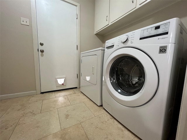 laundry area with cabinet space, light tile patterned floors, baseboards, and washing machine and clothes dryer