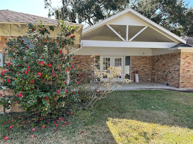 rear view of house featuring a carport, a patio area, brick siding, and a lawn