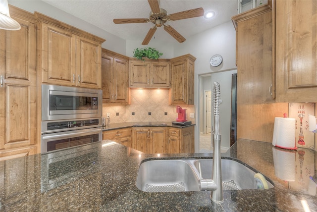 kitchen with decorative backsplash, appliances with stainless steel finishes, a ceiling fan, a textured ceiling, and dark stone countertops