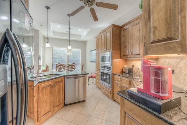 kitchen with brown cabinets, a raised ceiling, backsplash, appliances with stainless steel finishes, and a sink