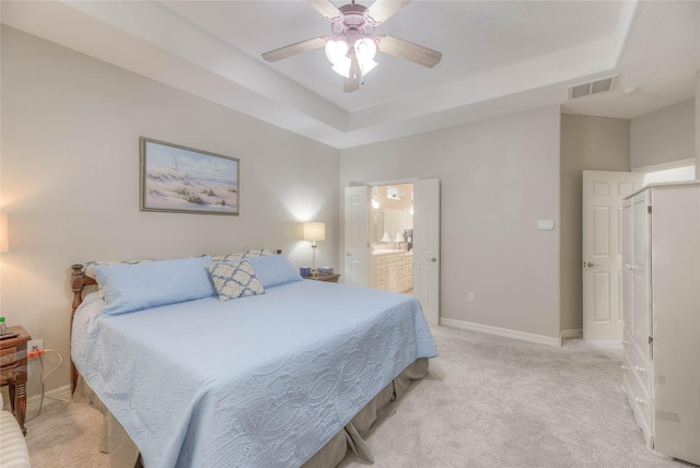 bedroom featuring light carpet, baseboards, visible vents, and a tray ceiling
